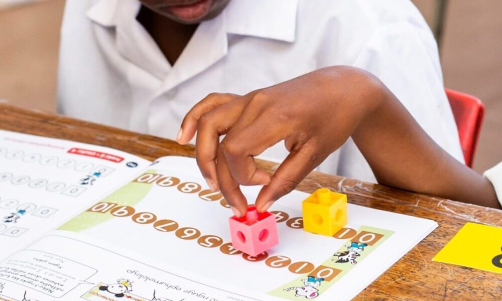 children_counting_maths Image showing a child's hands using blocks to complete a maths task in a workbook.